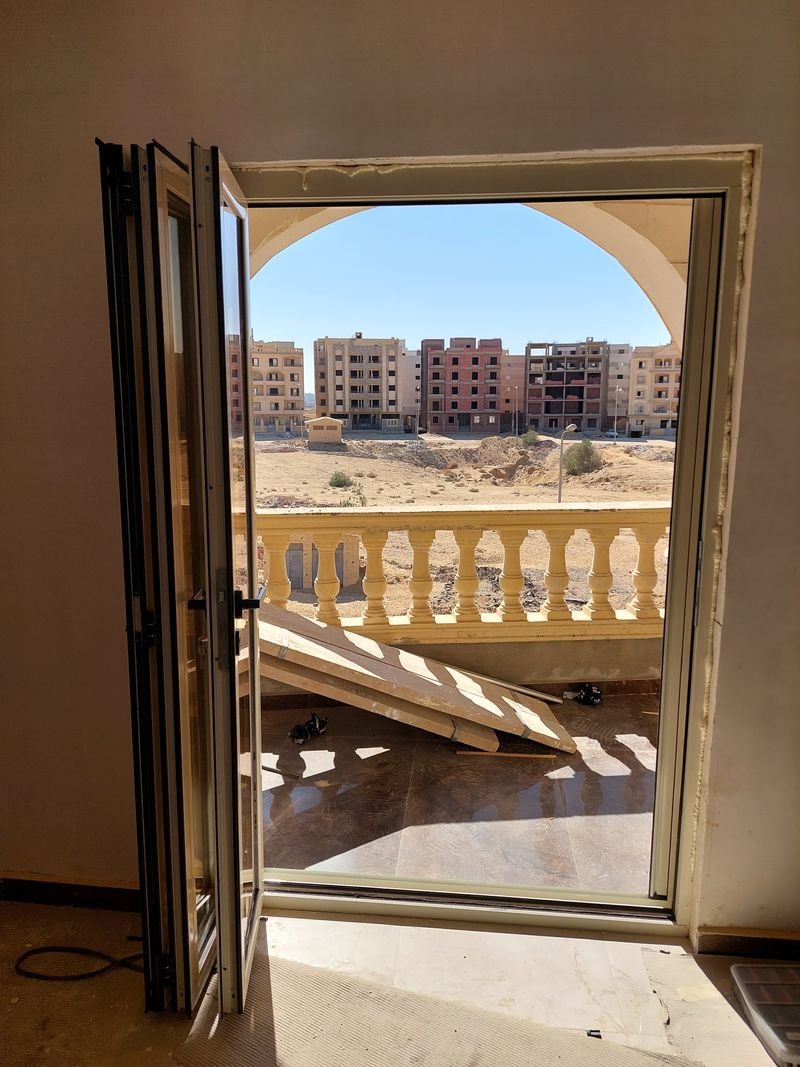 باب ألومنيوم مفصلي مفتوح نحو الشرفة